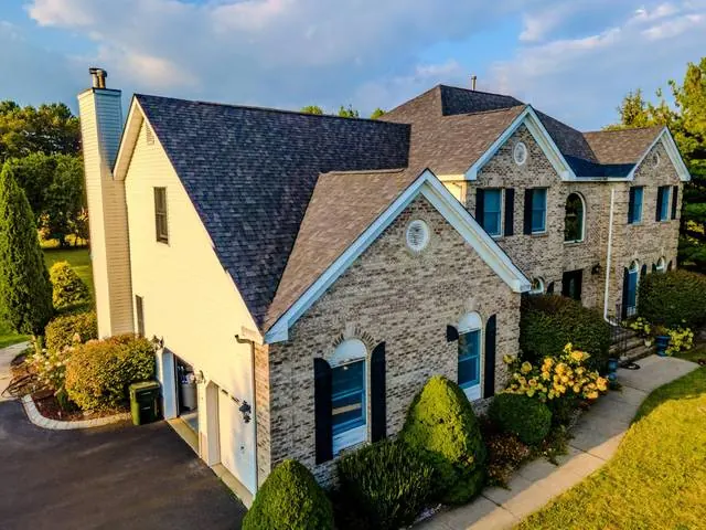 Aerial view of a new shingle roof on a stone and siding home