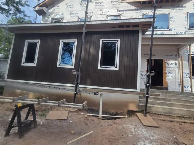 Dark vertical siding with white window trim