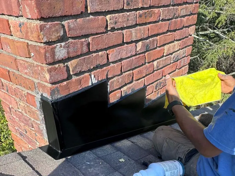 Installer sealing black chimney flashing