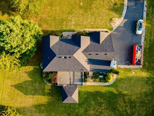 Top-down aerial view of a finished roof with a dumpster