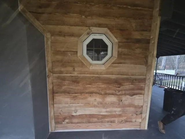 Wood siding with an octagon window under a porch