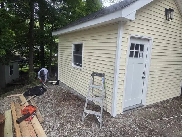 Yellow vinyl siding with white trim and a new door